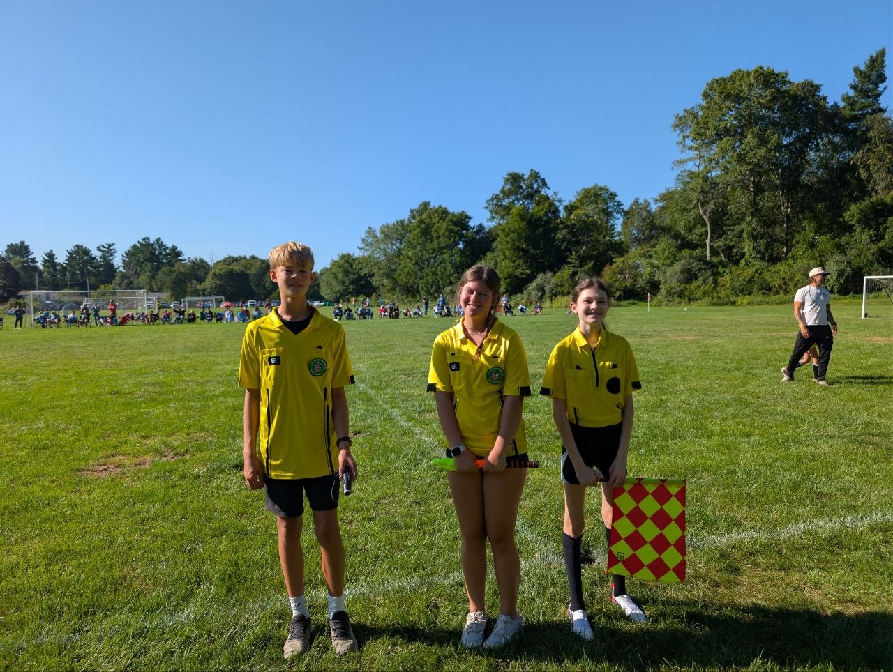 Three referees in yellow shirts on a soccer field