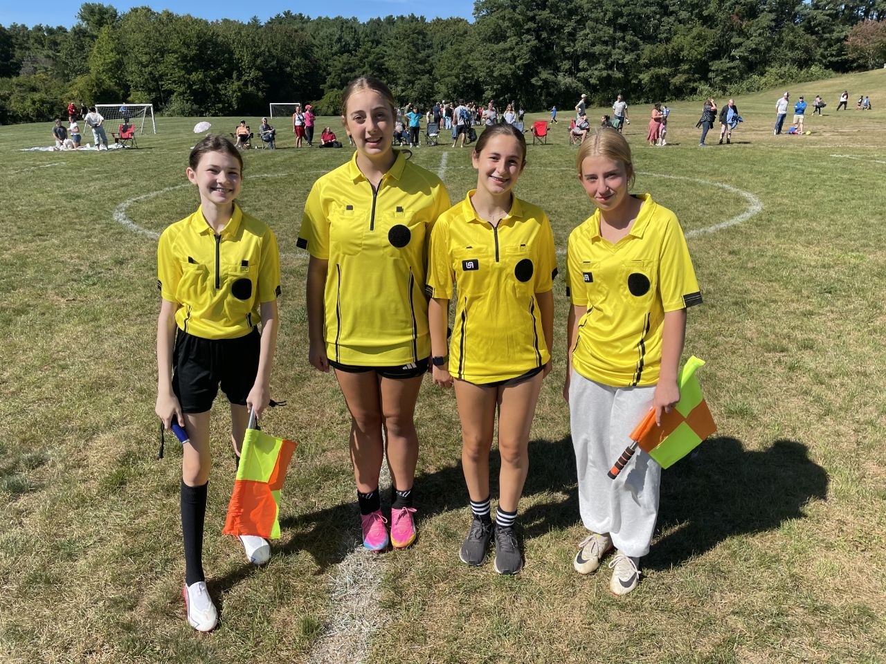 Four referees in yellow shirts on a soccer field